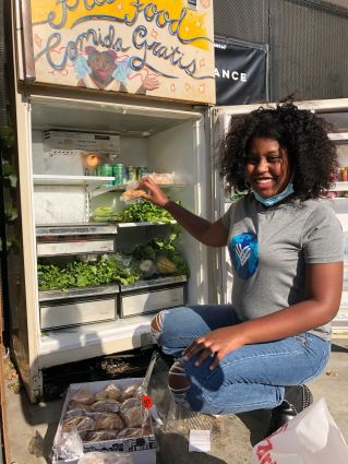 A black female activist looking at camera next to a food bank